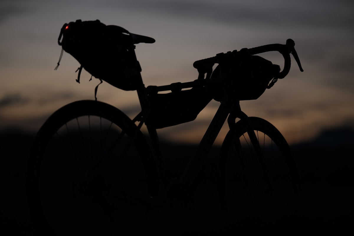 A bicycle loaded with adventure bags silhouetted against the sunset